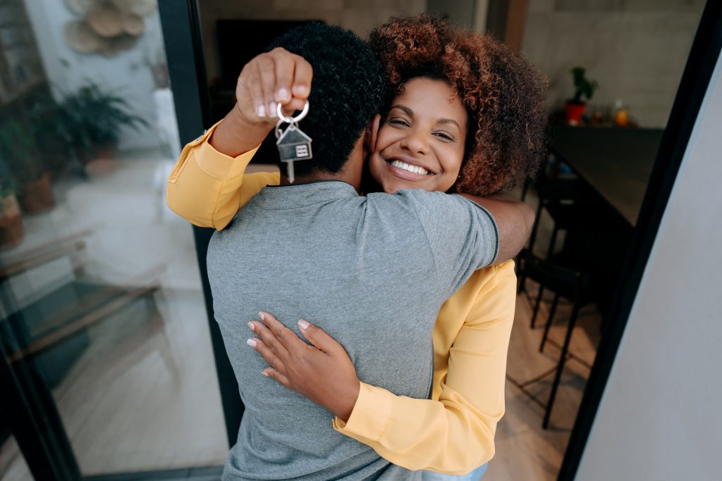 When is the Best Time to Buy a New Home? Ecstatic couple holding keys to new home