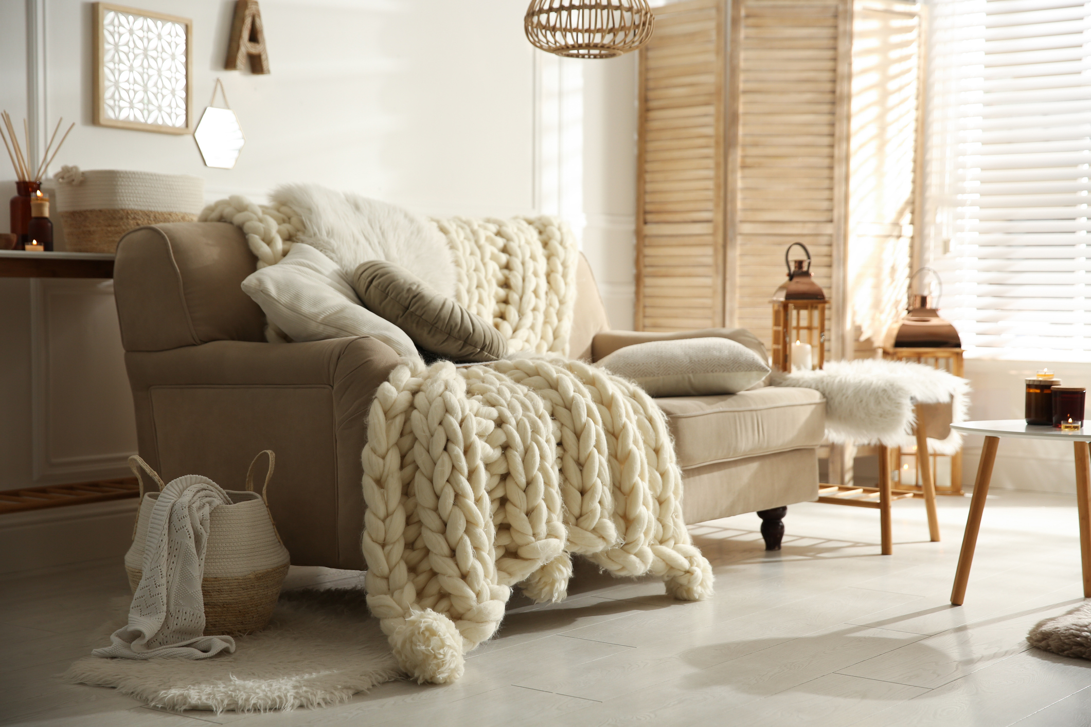 Cozy living room interior with beige sofa, knitted blanket and cushions