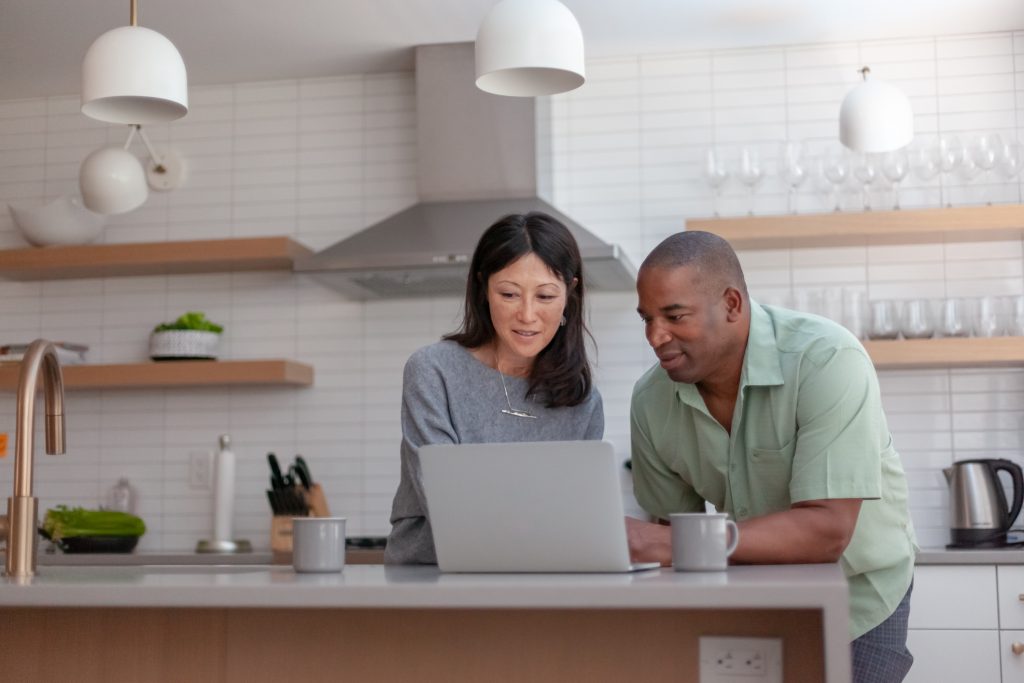 Downsizing What it is and How to Know if it’s Right for You. A mixed race couple use a laptop computer to pay bills online, manage budget and prepare tax documents. They are in the kitchen of their home.