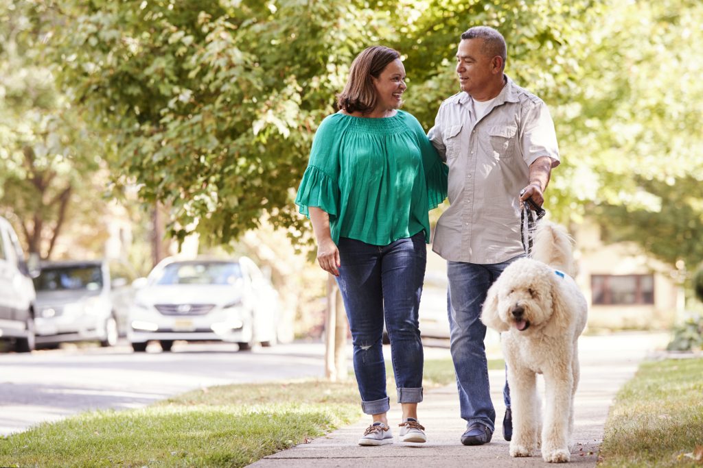 Downsizing What it is and How to Know if it’s Right for You. Senior Couple Walking Dog Along Suburban Street